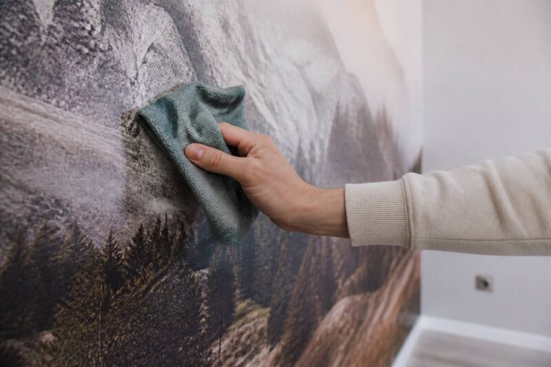Iemand neemt fotobehang voorzichtig af met een zachte microvezeldoek